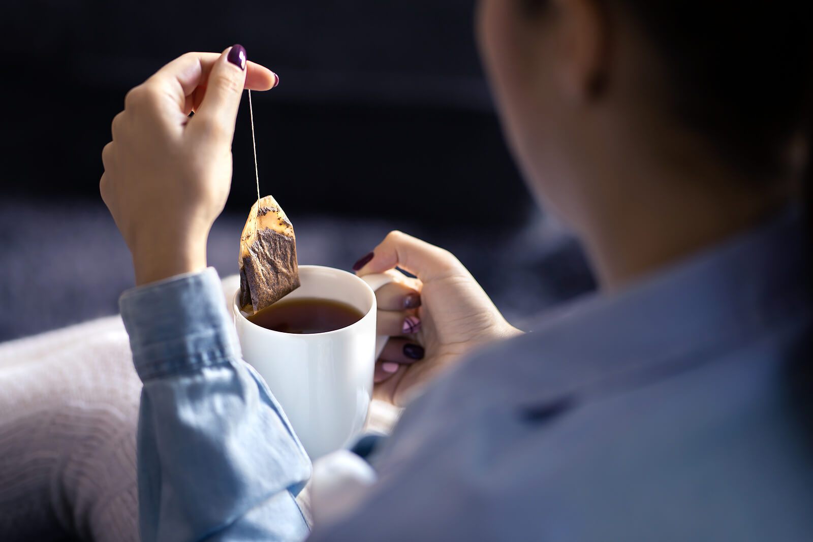 Une femme sortant un sachet de thé d'une tasse